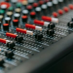 Vertical shot of a professional audio mixer with red potentiometers and switches.